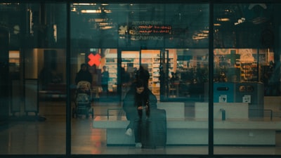 女人黑色外套站在玻璃墙面前
